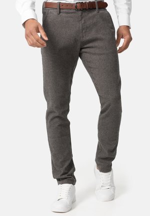 Grå teksturerede bukser med slim fit, der har et brunt læderbælte. Parret med hvide sneakers for et afslappet look.