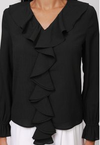 Schwarze Bluse mit langen Ärmeln, tiefem V-Ausschnitt und strukturiertem Stoff. Mit einem auffälligen Rüschendetail an der Vorderseite und gerafften Manschetten.