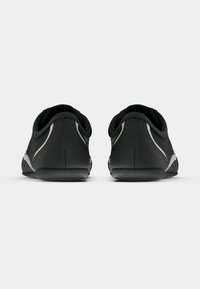 Sapatos pretos com acabamento em couro macio, formato arredondado, costura clara contrastante e solas de borracha. Apresentam um perfil baixo e bordas suaves.