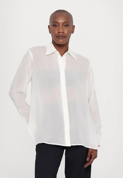 White, sheer button-up shirt with long sleeves, a pointed collar, and a straight cut. Features a subtle texture and contrasting white placket.