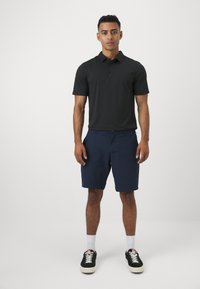 Melna īsām piedurknēm polo krekls ar trim pogām, apvienots ar tumši ziliem īsiem šortiem. Valkāts ar melniem sporta apaviem un baltām zeķēm. Vienkāršs, ikdienišķs dizains.
