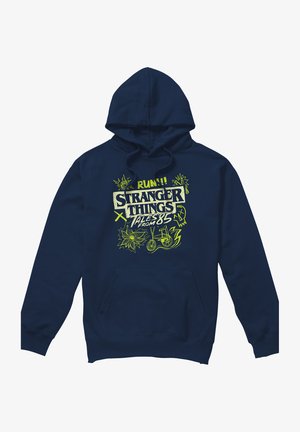 Navy blue hoodie with yellow-green "Stranger Things Tales from 85" text and doodles including a bike, flowers, lightning, and a skull.