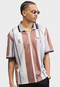 Short-sleeve polo shirt with vertical stripes in brown, beige, and blue. Features a black collar, Snoopy graphic, and logo patch on the chest.