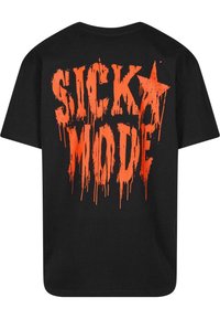 T-shirt en coton noir avec un grand texte orange coulant au dos, portant la mention "SICKO MODE". Col rond classique et manches courtes.