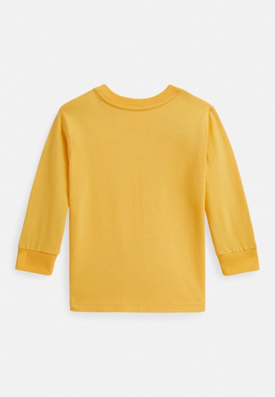 Gul langermet skjorte laget av myk bomull. Har rund hals og ribbestrikkede mansjetter. Glatt tekstur uten synlige mønstre eller grafikk.