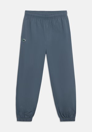 Pantalon de jogging gris foncé avec taille et chevilles élastiques et un petit logo crocodile vert sur la cuisse gauche.