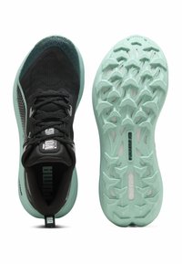 Baskets de sport noires avec un upper texturé, semelle extérieure vert menthe, et un design léger. Présente des accents réfléchissants et une semelle intérieure rembourrée.