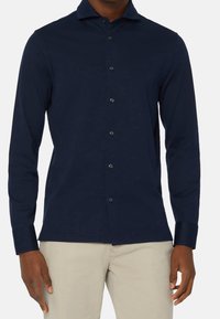 Námořnická košile s dlouhým rukávem z hladkého materiálu, s knopovým zapínáním, kontrastními knoflíky a klasickým límečkem.