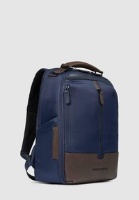 Zaino in tessuto blu navy con inserti in pelle marrone, dotato di una tasca frontale con cerniera, spallacci imbottiti e una maniglia superiore robusta.