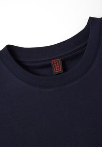 T-shirt in cotone blu navy con scollatura rotonda e cuciture piatte; presenta un'etichetta rossa e nera sul colletto che dice "STEFANEL."