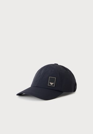 Casquette de baseball bleu marine foncé avec visière incurvée et petit écusson rectangulaire sur le panneau avant, présentée sur un fond clair uni.