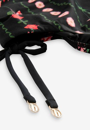 Costum de baie cu margine florală neagră, dotat cu bretele ajustabile negre și accente din metal auriu. Textură de material moale, design vibrant.