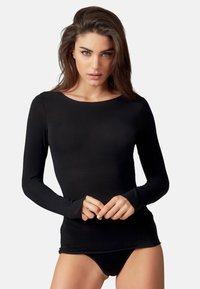 Maglia nera a maniche lunghe realizzata in un materiale morbido, con scollatura rotonda e design aderente, indossata sopra della biancheria intima nera.