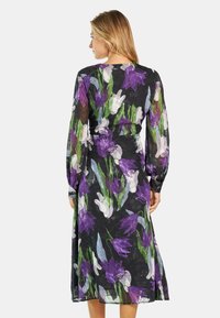 Langärmliges Kleid aus transparenter Stoff mit lila-weißen Blumenmustern auf schwarzem Hintergrund, mit lässiger Passform und gestuftem Rock.