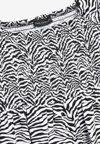 Sort/hvid zebra print gravidkjole med smocket bodice, samlet nederdel og en blød stoftekstur. Mærket læser "next MATERNITY."