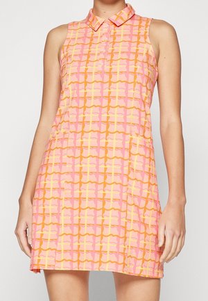 Vestido sin mangas con cuello, con patrón geométrico de cuadros en rosa, naranja y amarillo, llevado por una persona de pie con los brazos relajados.