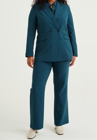 Tealfärgat skräddarsytt kostymset med en dubbelknäppt kavaj med två framfickor och matchande byxor. Slätt tyg med en strukturerad passform.