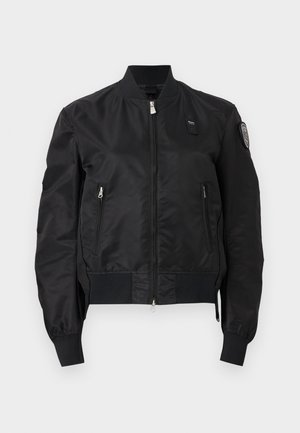 Svart bomberjakke med glidelås foran, glidelåslommer på sidene, ribbede mansjetter og kant, og logopatch på øvre venstre erme.