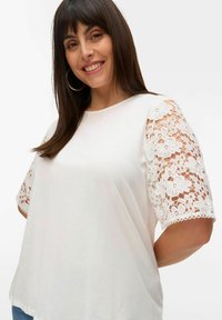 Witte t-shirt met korte kanten mouwen met bloemenpatronen. Zachte katoenen stof, relaxte pasvorm met ronde halslijn.