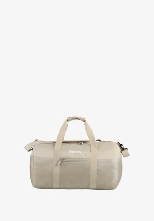 Sac de voyage beige en tissu durable, avec un panneau avant texturé, des poignées doubles et une bandoulière réglable.