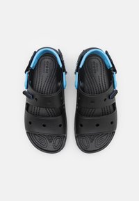 Sandales noires avec une surface texturée, trois larges brides et des accents bleus réglables sur une bride rembourrée autour de la cheville. Convient pour un port confortable.