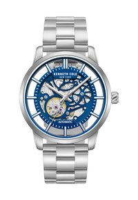 Montre automatique en acier inoxydable argenté avec un cadran squeletté bleu. Présente des marques horaires bien visibles, des engrenages ouverts et un bracelet en maillons métalliques.