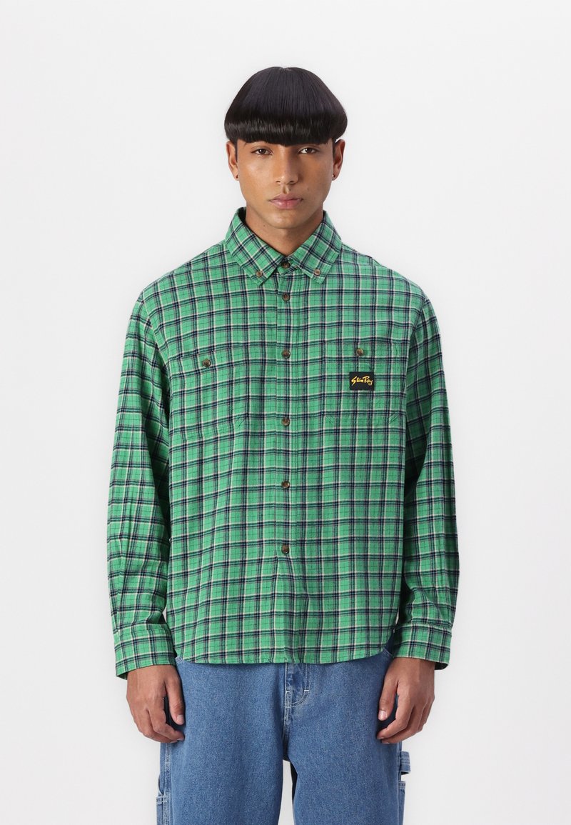 Green plaid shirt made of fabric, featuring a button-up front, long sleeves, chest pocket with logo, and relaxed fit. Casual design.