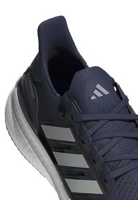 Zapatilla de correr de color navy con parte superior de malla, acentos texturizados, tres rayas plateadas y una suela media blanca; cuenta con un collar acolchado y cordones.