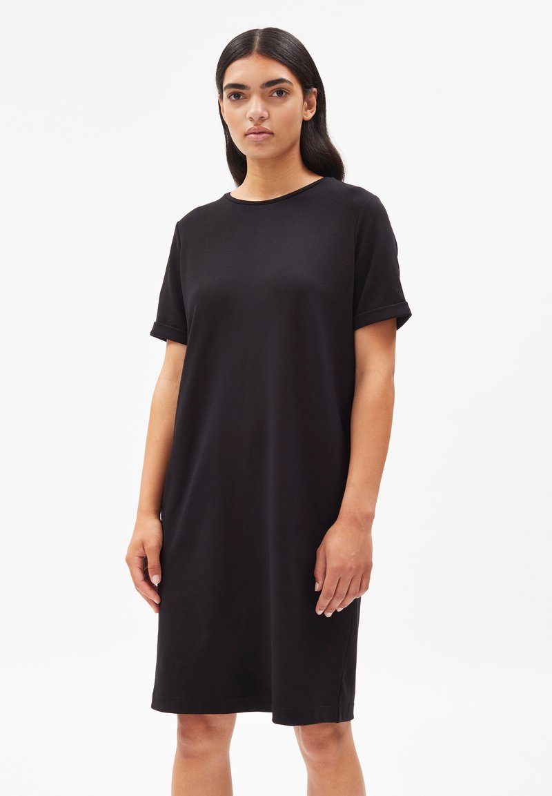 Robe t-shirt en coton noir avec des manches courtes, coupe décontractée, encolure ronde et ourlet au niveau des genoux. Texture lisse et détails de design minimalistes.