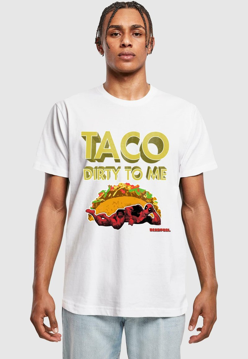 T-shirt en coton blanc avec un texte audacieux jaune disant « TACO DIRTY TO ME » accompagné d'un graphique de Deadpool allongé sur un taco.