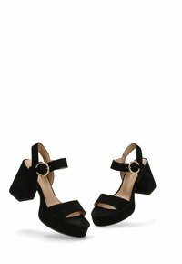 Sandalias de tacón alto de ante negro con tacón de bloque, punta abierta, tiras anchas y una correa para el tobillo con un detalle de hebilla circular dorada.