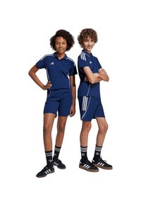Zwei Kinder tragen gleichfarbige navyfarbene Sportoutfits mit weißen Streifen. Das Design umfasst kurze Ärmel und Shorts, mit Adidas-Logo.