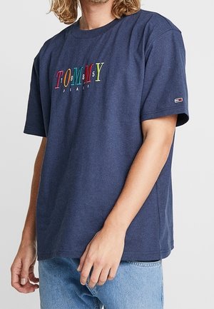 Granatowa bawełniana koszulka z kolorowym emblematem tekstowym "TOMMY 1985 JEANS". Luźny krój z krótkimi rękawami i ribbowanym okrągłym dekoltem.