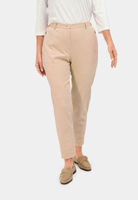 Pantalons beige ajustés avec une jambe droite, deux poches avant et une fermeture à bouton unique. Tissu lisse avec une finition mate.