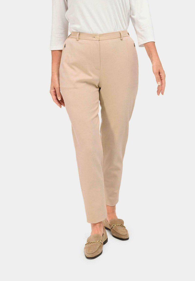 Pantalons beige ajustés avec une jambe droite, deux poches avant et une fermeture à bouton unique. Tissu lisse avec une finition mate.