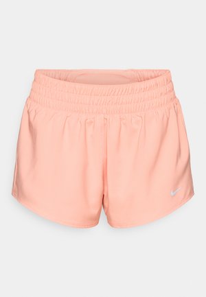 Peach-colored athletic shorts with an elastic waistband and side seams. Features a small white Nike logo on the bottom right. Smooth fabric.