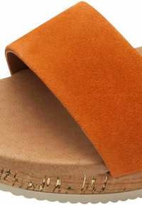 Orange ruskinds slide sandals med en bred rem, kork mellemsål og tekstureret beige fod seng. Bemærkelsesværdige hvide accenter på sålen.