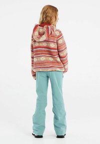 Fleece hoodie in rood en beige gestreept patroon, met een capuchon en bloemaccenten. Draagt in combinatie met lichtblauwe sneeuwbroeken en zwarte laarzen.