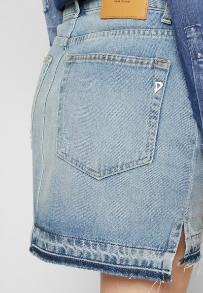 Saia de denim azul claro com bainha desfiada, fendas laterais e bolsos traseiros. Apresenta uma etiqueta de couro castanho e detalhes de costura discretos.