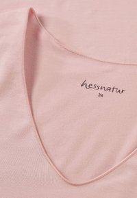 Light pink, soft fabric shirt with a wide scoop neckline. Features a label reading "hessnatur 36" near the collar. Smooth texture, minimal detailing.