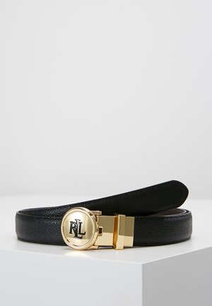 Ceinture en cuir noir avec une boucle ronde en or présentant les initiales entrelacées « RL », exposée enroulée sur une surface blanche.
