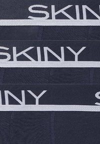 Fasce di cintura di underwear navy impilate con testo bianco "SKINY" e strisce bianche orizzontali su ogni fascia.