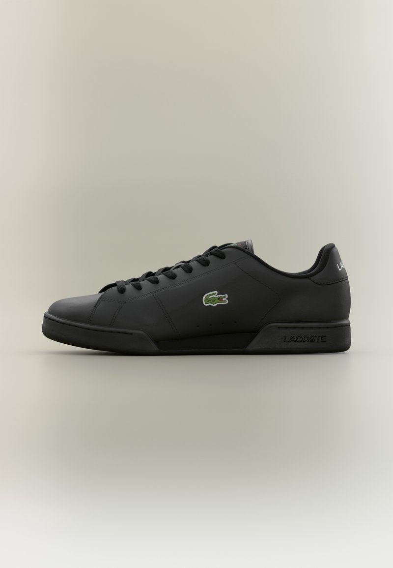 Baskets basses en cuir noires Lacoste avec lacets noirs, logo crocodile vert sur le côté et "Lacoste" embossé sur la semelle.