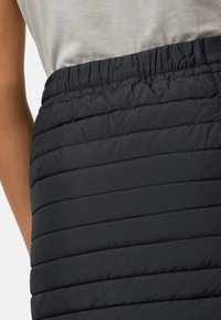 Zwarte pufferrok met horizontaal gestikte structuur en elastische tailleband, gemaakt van een glad synthetisch materiaal. Geen zichtbare sluitingen.