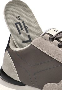 Zapatilla de ante gris con suela negra, que muestra una plantilla ventilada etiquetada como "40". Presenta un diseño suave, con detalles de costura en contraste.