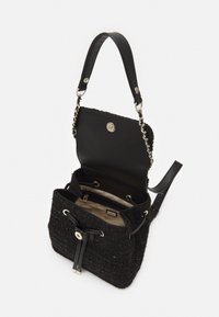 Sac à main tressé noir avec un extérieur texturé, une anse en cuir et des détails en métal argenté. Il possède une fermeture à cordon et un intérieur spacieux.