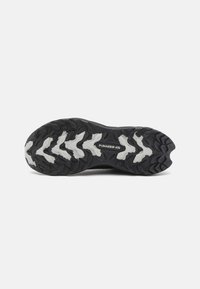 Semelle de sneaker en caoutchouc noir avec des profondes rainures et un logo PUMA Grip ATR blanc. Surface texturée avec un design en zigzag prononcé pour une meilleure adhérence.