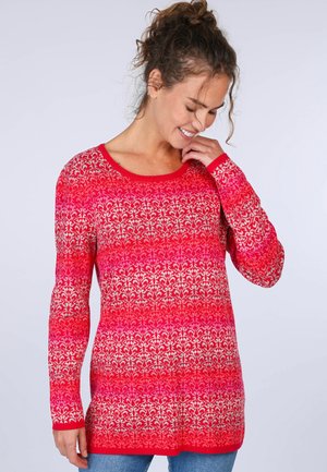 Strickpullover in leuchtendem Rot mit einem strukturierten Blumenmuster, langen Ärmeln und rundem Ausschnitt, kombiniert mit blauen Jeans.
