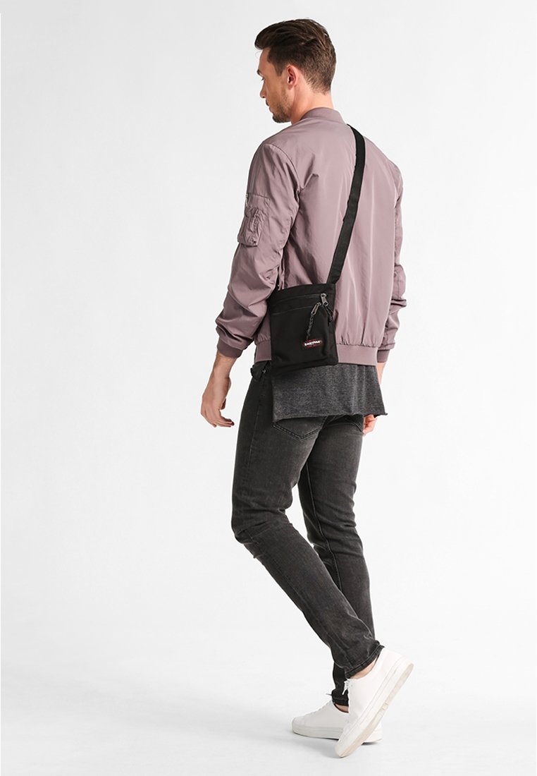 Borsa a tracolla nera, forma rettangolare, materiale resistente, presenta una tasca con zip, design minimalista e tracolla regolabile.