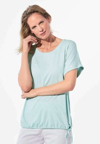 Lichtblauw casual top met een ronde hals, korte mouwen en een trekkoord onderaan met kleine perforaties door de stof.